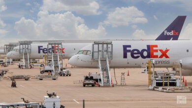 Purple-tailed FedEx cargo planes waiting on the tarmac, with ladders up to pilot door.