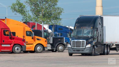 A black tractor with a white trailer pulling into a truckstop