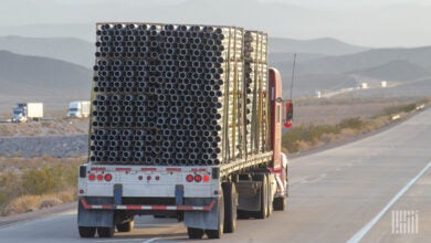 A flatbed trailer hauling piping on a highway