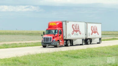 A red Saia daycab pulling two Saia pup trailers