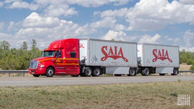 A red Saia tractor pulling two Saia pup trailers