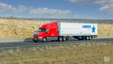 A red tractor pulling a Landstar trailer on a highway