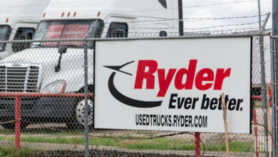 A Ryder sign on a fence surrounding a dealership