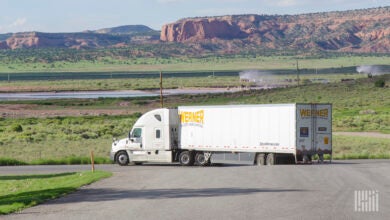 A tractor leaving a facility with a Werner dry van trailer