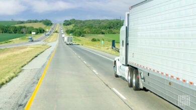 A white sleeper cab pulling a white trailer on a highway