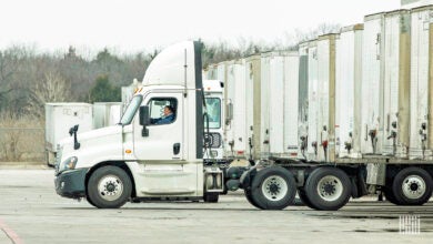 A white tractor hooking a white trailer at a yard