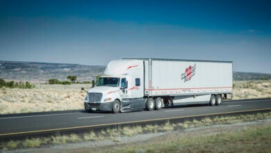 A white tractor pulling a white Heartland dry van trailer on a highway