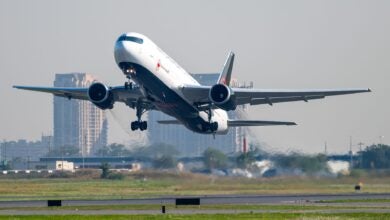 An Air Canada jet with black belly lifts off runway, coming toward viewer.