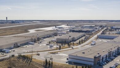 Aerial view of warehouses at an airport with planes in the distance.