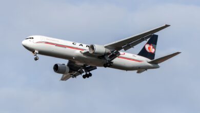 A Cargojet plane with dark blue tail seen from below as it approaches an airport.