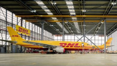 Yellow DHL cargo jets inside a large hangar.