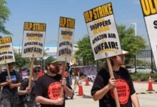 Workers with signs picket for better treatment outside an Amazon facility.