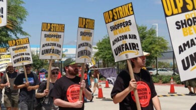 Workers with signs picket for better treatment outside an Amazon facility.