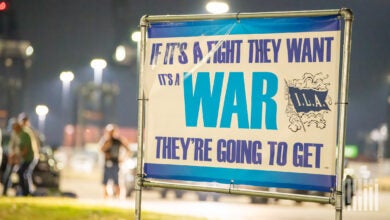 Image shows a longshore union sign that says "If it's a fight they want it's a war they're going to get"