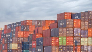 Image shows stacked shipping containers.