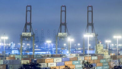 Image shows container cranes and containers at night.