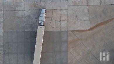 A tractor-trailer is seen from above as it drives in a parking lot.