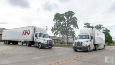 Two XPO daycabs pulling trailers near a terminal